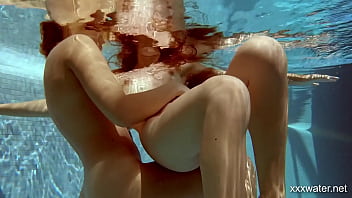 In the indoor pool, two stunning girls swim